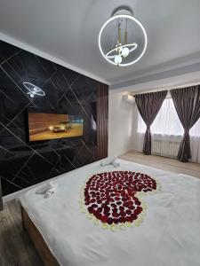 un lit avec un bouquet de roses rouges sur le lit dans l'établissement LUXE APARTMENTS, à Almaty