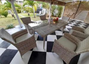 a patio with a table and chairs on a checkered floor at Beehive in Pamplemousses Village
