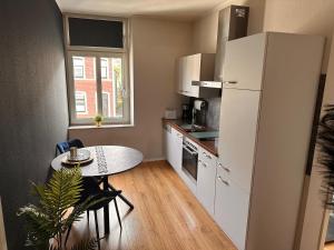 a small kitchen with a table and a white refrigerator at Stylische Studios Würselen Nähe Aachen, WLAN, Netflix, kostenlose Parkplätze, modern & gemütlich in Würselen
