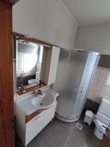 een witte badkamer met een douche en een wastafel bij Dinos Pool Apartment in Kardamaina