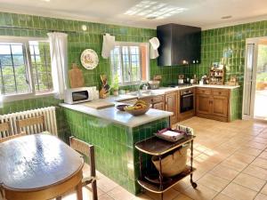 a kitchen with green tiles on the walls and a table at Casa del Cielo CostaBravaSi in Santa Cristina d'Aro