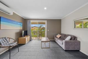 a living room with a couch and a tv at Sapphire Beach Poolside Retreat in Kororo Basin