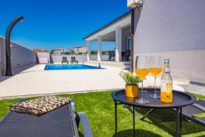 een tafel met twee glazen wijn bovenop een tuin bij Villa Tea with heated pool in Loborika
