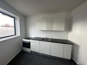 a white kitchen with a sink and a window at Airport Room in Copenhagen