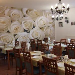 a dining room with tables with white roses on the wall at Penzión Pulse in Podhájska