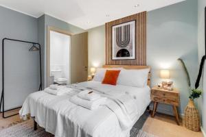 a bedroom with a large bed with white sheets and orange pillows at City Stays Luxury Townhouse in Canterbury, sleeps 6 in Canterbury