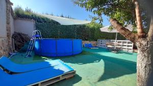 a playground with a blue slide and a tree at VIVENCIAS casa rural para 10 personas in Camuñas