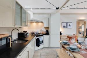 una cucina con armadi bianchi e tavolo in legno di City Stays Hideaway Luxury Townhouse in Canterbury, sleeps 6 a Canterbury