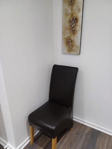 a black chair sitting next to a white wall at Beautiful maisonette in Leeds