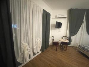 ジェノヴァにあるB&B Cavour16のテーブル、椅子2脚、カーテンが備わる客室です。