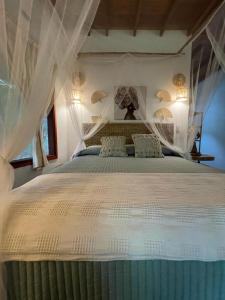 a bedroom with a large white bed with curtains at El Retiro De Carolina in Santa Marta