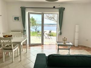 a living room with a table and a view of the water at Rosmarin Apartments Sea View Garden Side in Jadranovo