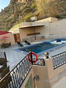 a house with a swimming pool next to a mountain at إستراحة وادي بني خالد in Dawwah
