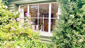 una ventana en una casa verde con flores en Casita excelente ubicación en San Carlos de Bariloche