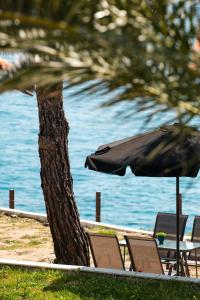 Acroterra - Easy Living في أليكي: طاولة وكراسي ومظلة بجانب الماء