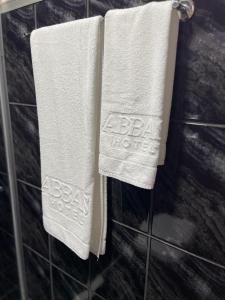 two towels with the words bbc hotel on them hanging in a bathroom at Abbas Hotel in Uberlândia