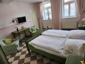 a bedroom with a bed and two chairs and a television at Hotel zur Post in Wernigerode
