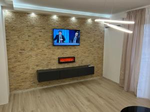 ein Wohnzimmer mit einem TV an einer Backsteinwand in der Unterkunft Apartman Central Lux A&D in Bečej