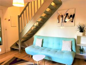 ein Wohnzimmer mit einem blauen Sofa und einer Treppe in der Unterkunft CAPORIZON-Carsac-Piscine-Gite Périgord Sarlat-Clim in Carsac-Aillac
