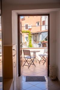Une porte ouverte s'ouvre sur un balcon avec une table et des chaises. dans l'établissement Apartment Uno, à Koper