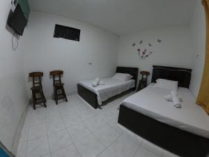 Habitación con 2 camas y 2 taburetes en Hospedaje Manuel Valdés, en San Agustín