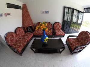 Hospedaje Manuel Valdés في سان أوغستين: غرفة بها مجموعة من الكراسي و مزهرية على طاولة