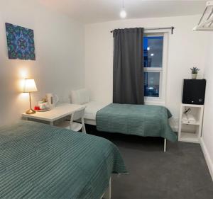 a hotel room with two beds and a window at Lord Merit Guest Rooms in King's Cross St Pancras in London