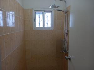 a bathroom with a shower and a window at Modern Bungalow with private pool and patio in Old Yundum