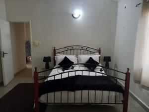 um quarto com uma cama com almofadas pretas e brancas em Modern Bungalow with private pool and patio em Old Yundum