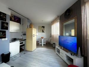 a living room with a television and a kitchen at Tranquillité à 30 min de Paris in Poissy
