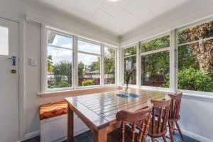 a dining room with a table and chairs and windows at Lush Oasis - Blenheim Holiday Home in Blenheim