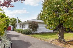 a white house with a tree and a driveway at Lush Oasis - Blenheim Holiday Home in Blenheim