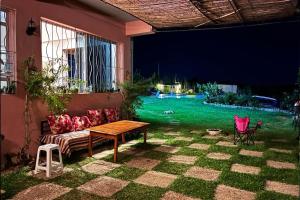 patio con divano, tavolo e cortile verdeggiante di jnan Lemonie a Asilah