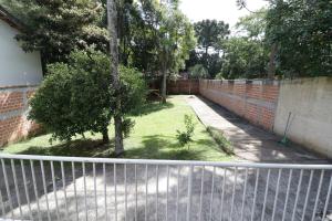 einen Zaun vor einem Hof mit einem Baum in der Unterkunft Opera Hostel in Curitiba