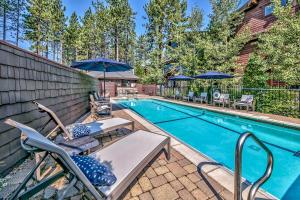 a pool with chairs and umbrellas next to a house at The PEAK Rubicon 11 - The Ultimate in Lakefront Luxury in South Lake Tahoe