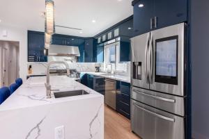 a kitchen with blue cabinets and a stainless steel refrigerator at Prime Location, Stylish Space: 3BR Home with BBQ in Los Angeles