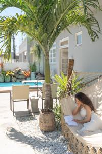 a woman sitting in a hammock under a palm tree at Pousada Praia Pajuçara in Maceió