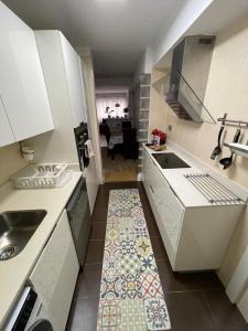 a kitchen with white cabinets and a tile floor at Kukis Duplex Beach near Bilbao in Getxo