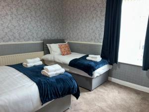 a bedroom with two beds with towels on them at Homely 3 Bed House Halifax in Exley