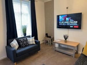 a living room with a couch and a tv at Homely 3 Bed House Halifax in Exley