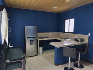 een keuken met blauwe muren en een koelkast bij Mini casa, Vara Blanca in Heredia