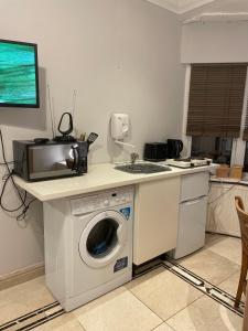 a kitchen with a washing machine and a microwave at North London Studio Apartment in London