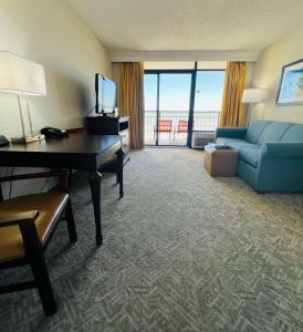 a hotel room with a couch and a desk and a living room at Best Western Ocean Sands Beach Resort in Myrtle Beach