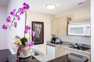 una cocina con flores púrpuras en un jarrón en un mostrador en Campus Tower Suite Hotel en Edmonton