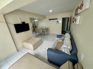 sala de estar con sofá azul y TV en Beira-mar na praia de pajuçara com Dois quartos - Apto 304, en Maceió