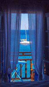 a window with a view of the ocean and a boat at Thalassopoulia -Zephyrus Room in Ayía Kiriakí