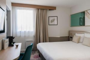 um quarto de hotel com uma cama, uma secretária e uma janela em Brit Hotel Orléans St Jean de Braye - L'Antarès em Saint-Jean-de-Braye