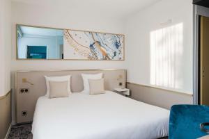 1 dormitorio con cama blanca y espejo en Brit Hotel Orléans St Jean de Braye - L'Antarès, en Saint-Jean-de-Braye