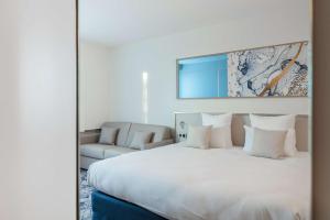 sypialnia z dużym białym łóżkiem i kanapą w obiekcie Brit Hotel Orléans St Jean de Braye - L'Antarès w mieście Saint-Jean-de-Braye