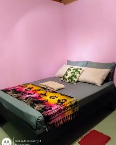Cama en habitación con pared de color rosa en El Tucán Feliz - Jungle tiny guest house by Playa Cocles en Cocles